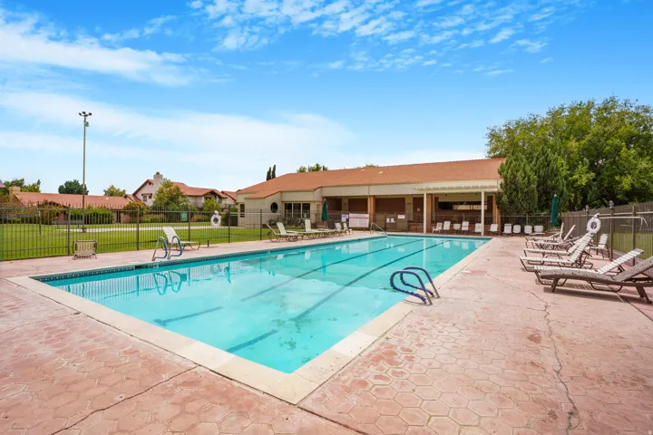 Expansive outdoor swimming pool with lane markers, surrounded by a textured concrete deck