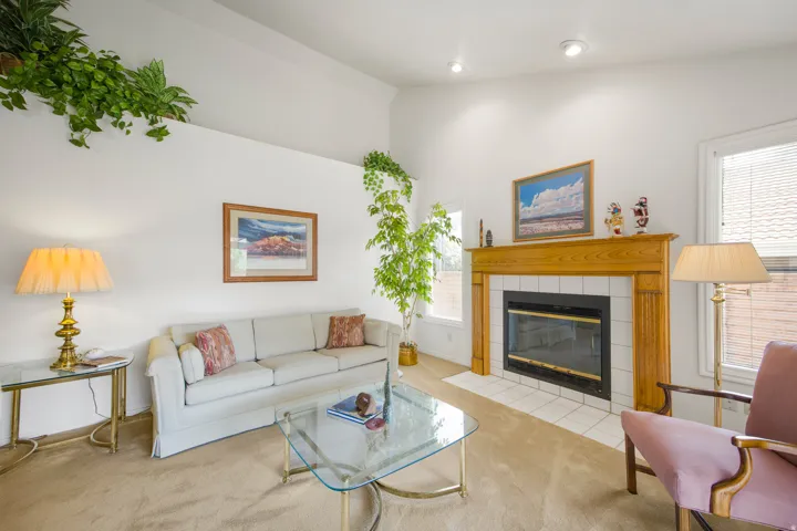 Vaulted ceiling, recessed lighting, fireplace with tile surround, wood mantel, and carpeted flooring