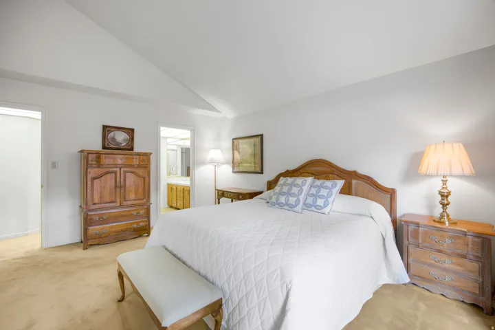 Vaulted ceiling, wall-to-wall carpeting, and a built-in vanity with wood-finish cabinetry