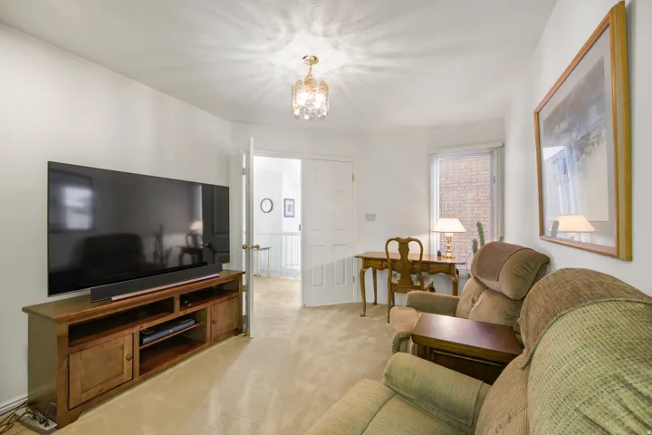 Recessed window, double French doors, decorative chandelier, and light-toned carpeting