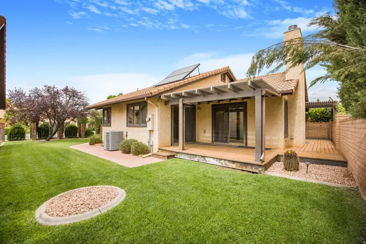 Expansive lawn area with a tiled patio, covered pergola, and a wooden deck