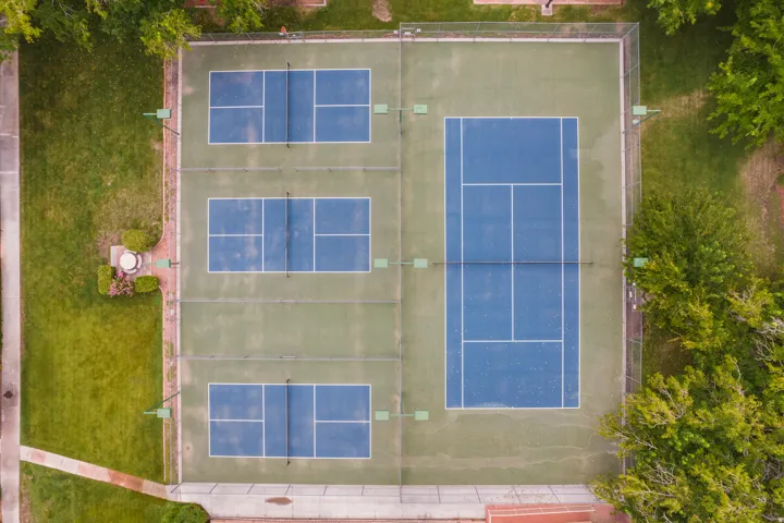 Multiple blue-surfaced courts with green surrounds