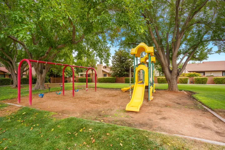 Community playground featuring a swing set, slide structure, and surrounding grassy area