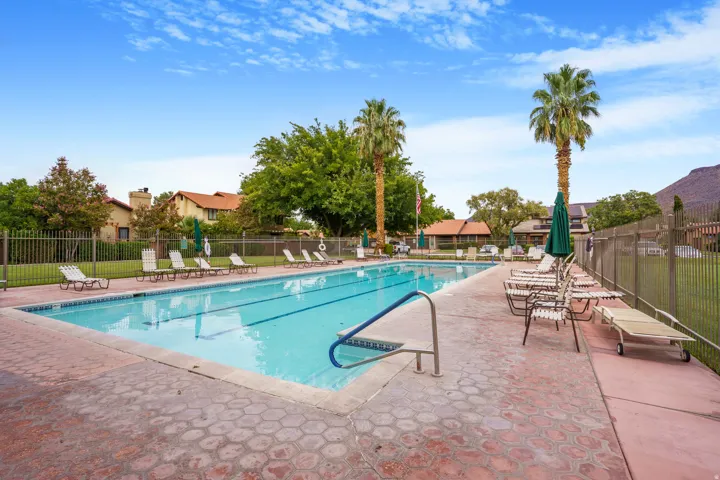 Community swimming pool featuring a lap lane, surrounding lounge area, and mature palm trees
