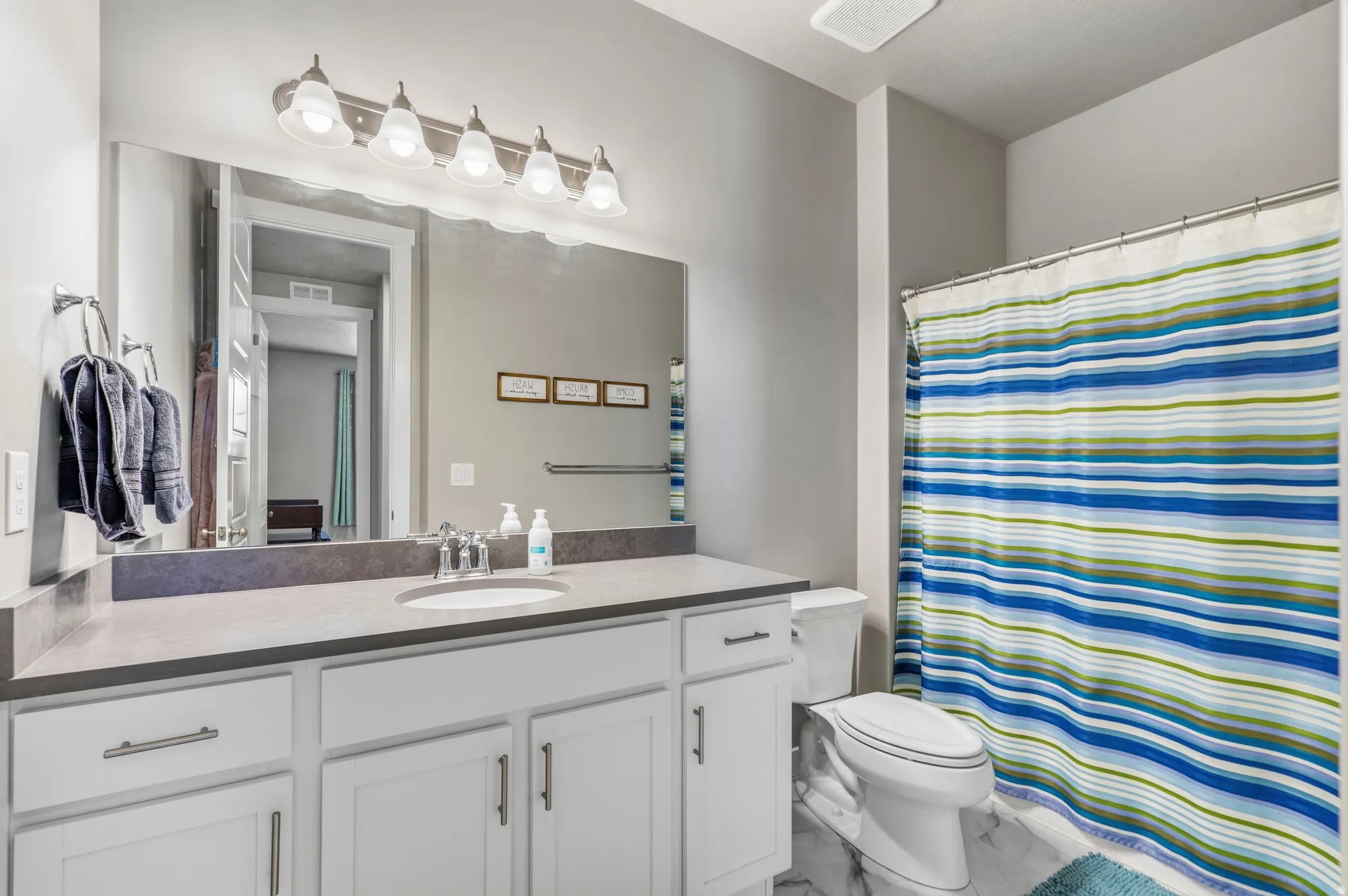 Vanity with white cabinetry, integrated sink, and gray countertop