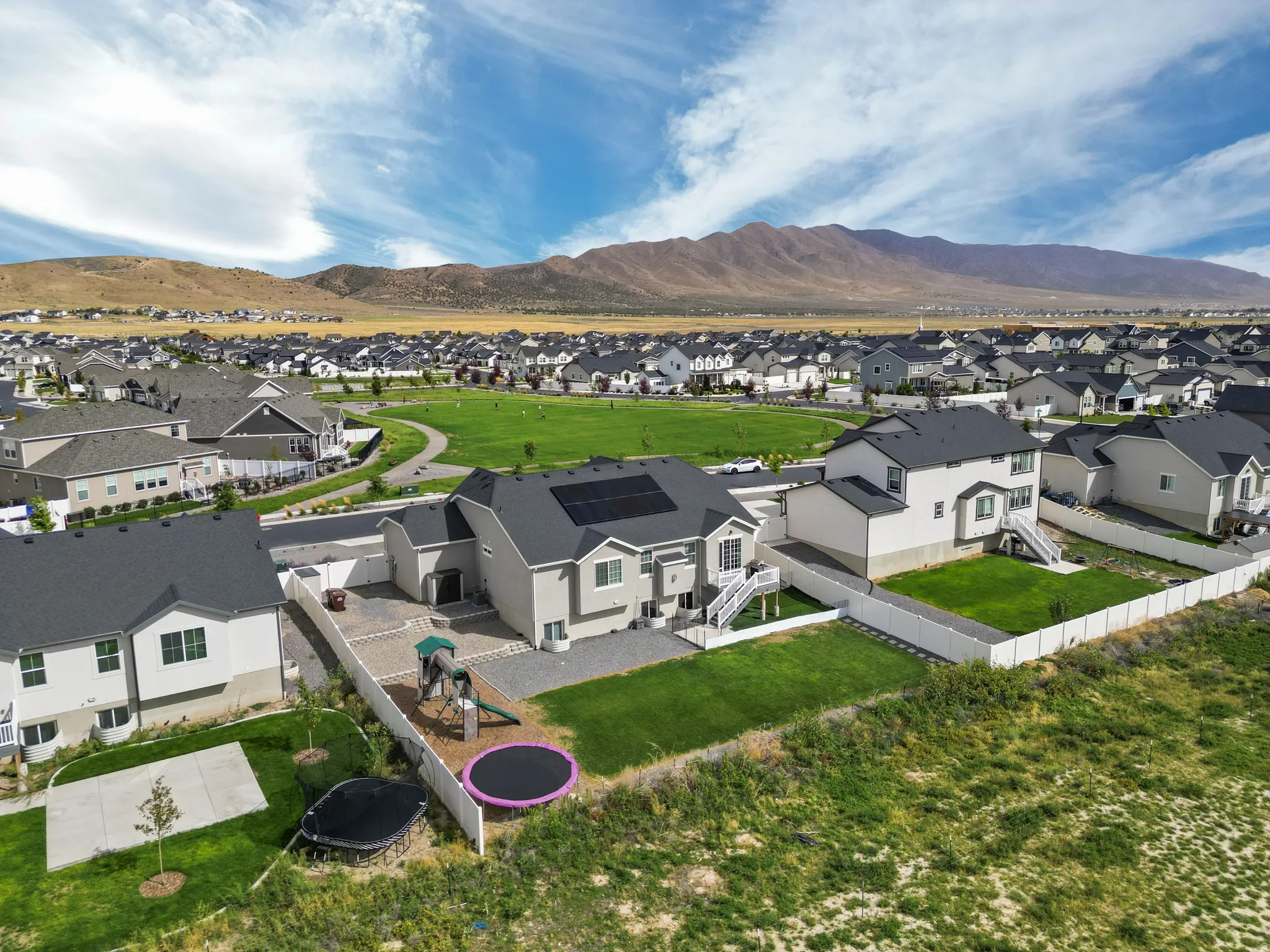 Mountain backdrop, expansive green spaces, structured residential community, and solar panels