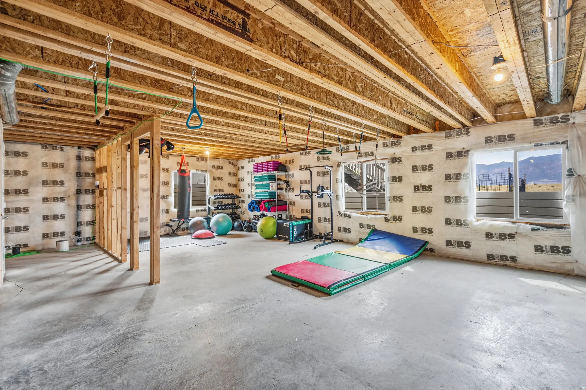 Unfinished basement space featuring exposed wood joists, concrete flooring, and multiple windows