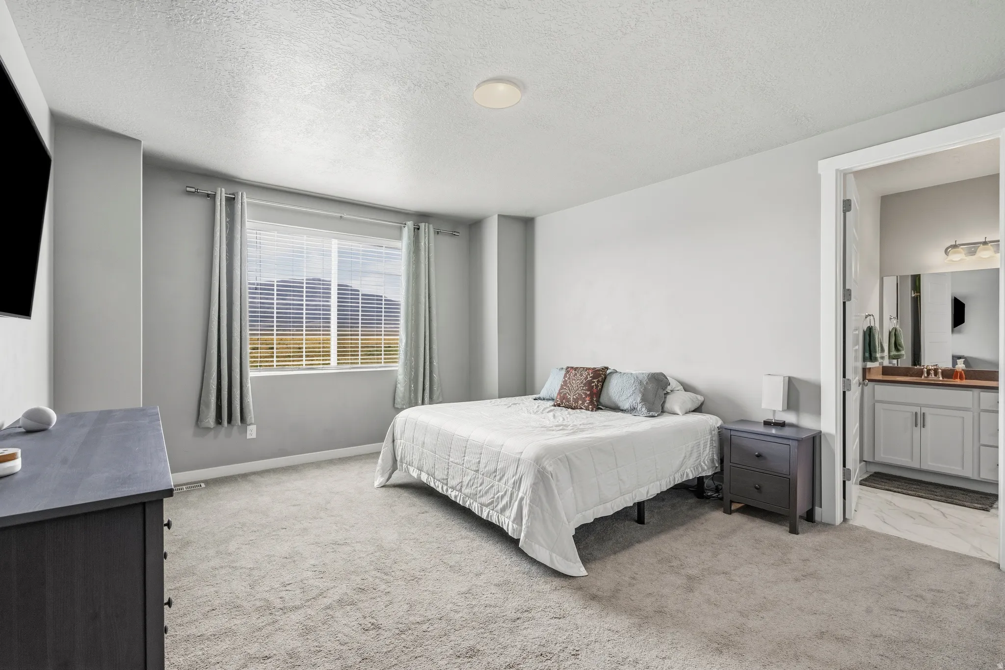 Wall-to-wall carpeting, recessed ceiling lighting, and a window with blinds and curtains