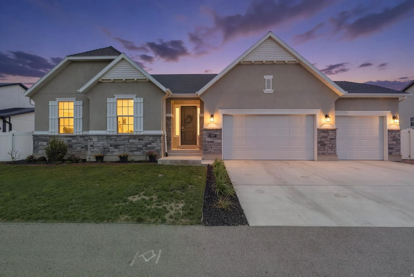 Stucco exterior with stone accenting, prominent gables, decorative window shutters, and an attached three-car garage