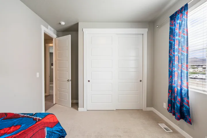 Plush carpet flooring, white paneled closet doors, and a window with blinds