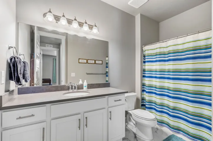 Vanity with white cabinetry, integrated sink, and gray countertop
