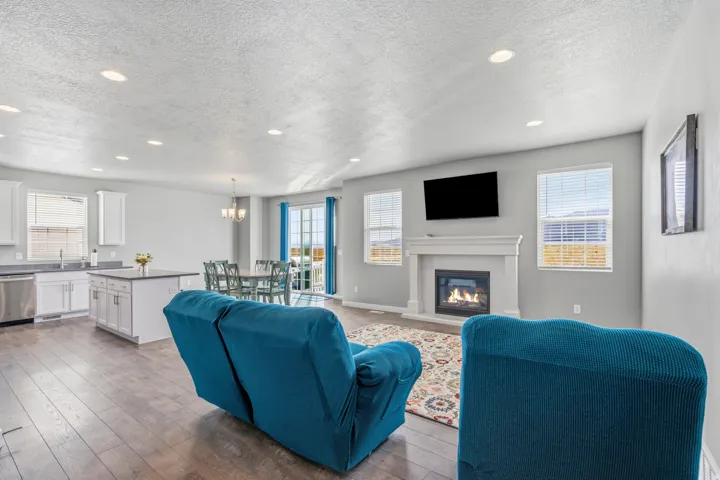 Open concept living area featuring wood-finish flooring, a white kitchen with an island, and stainless steel appliances