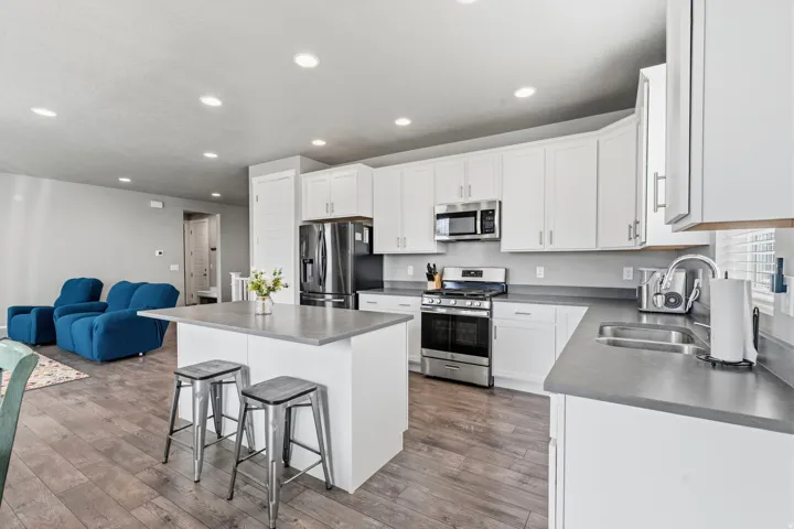 Kitchen featuring white cabinetry, stainless steel appliances, a center island with countertop seating, and wood-finish flooring