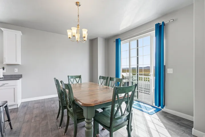 Dining area featuring wood-finish flooring, a brass-tone chandelier, and a sliding glass door