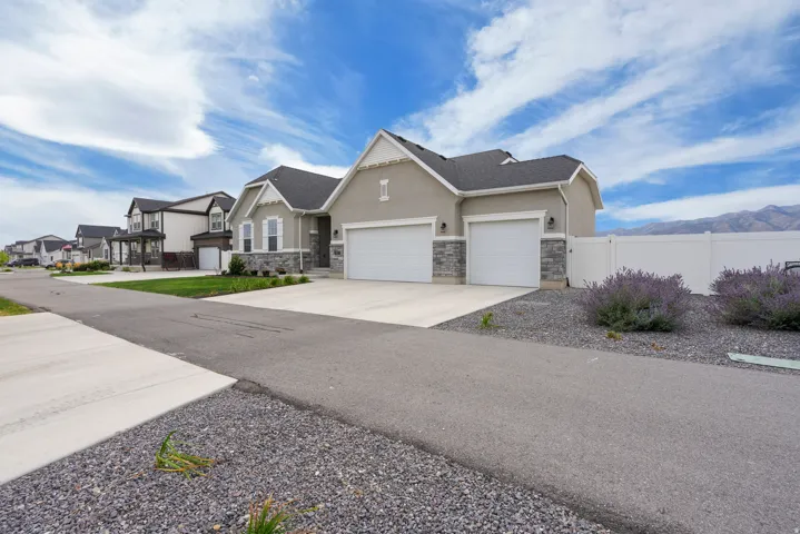 Contemporary stucco exterior with stone accents, dual garage doors, and a concrete driveway