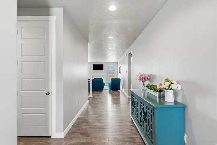 Recessed lighting illuminates the hall with wood-finish flooring and light-toned walls