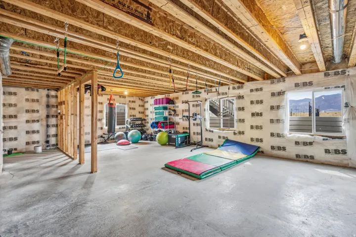 Unfinished basement space featuring exposed wood joists, concrete flooring, and multiple windows