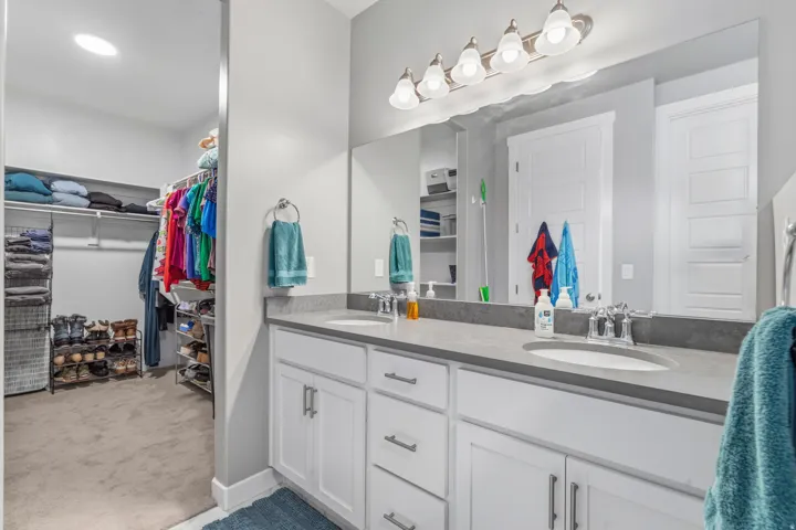 Double vanity with integrated sinks, gray countertop, white cabinetry, and brushed nickel fixtures