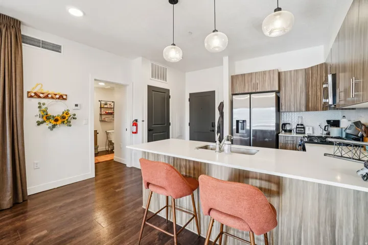 Modern kitchen featuring stainless steel appliances, wood-finish cabinetry, a large island with a countertop, and pendant lighting