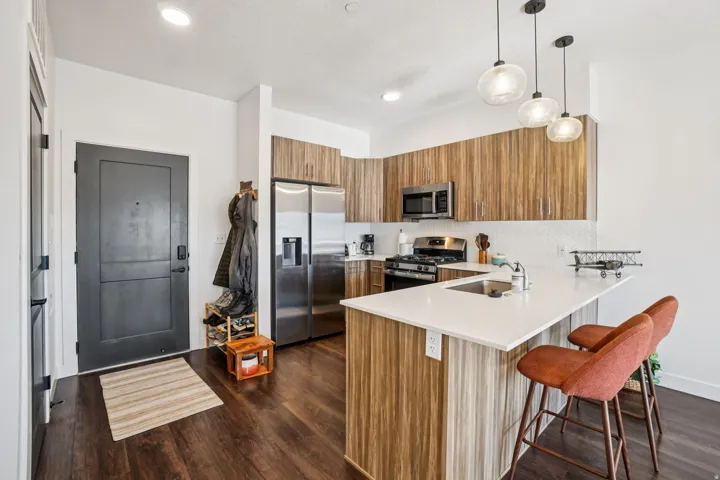 Full kitchen featuring stainless steel appliances, wood-finish cabinetry, and a white countertop island with seating