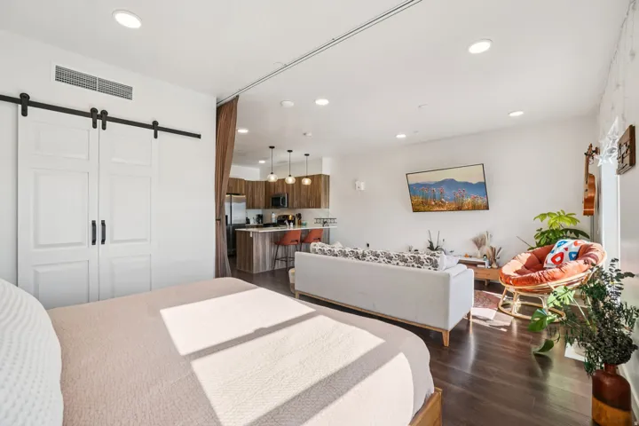 Open-concept living area with dark wood-finish flooring, recessed lighting, and kitchen with wood cabinetry