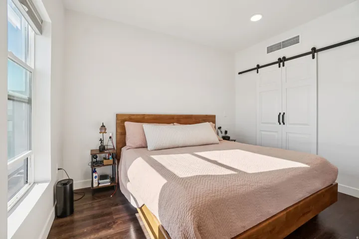 Wood-finish flooring, a large window, recessed lighting, and a barn door closet with black hardware