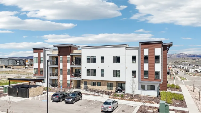 Contemporary multifamily building featuring a stone and wood-finish facade, multiple private balconies, and dedicated parking