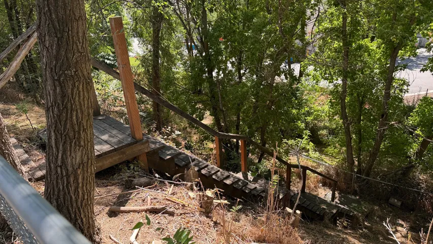 Terraced wood staircase with natural wood railings, set among mature trees and natural landscaping