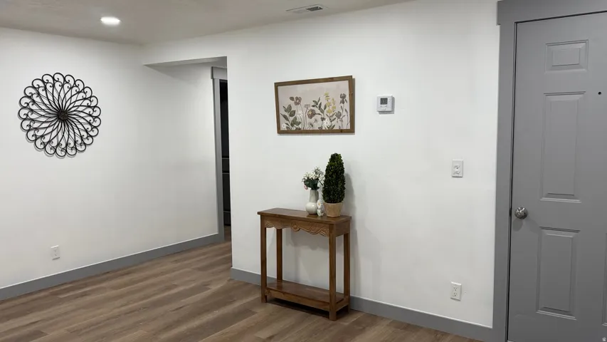 Recessed lighting, wood-finish flooring, white walls, and a paneled interior door