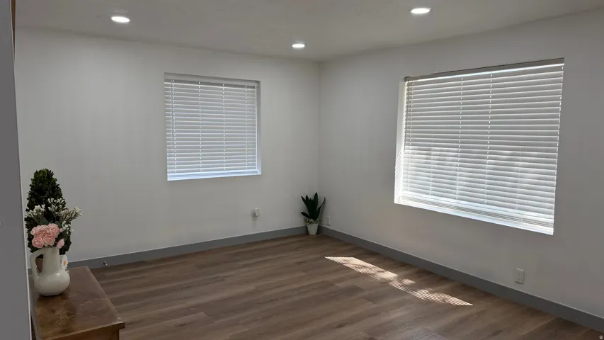 Recessed lighting, wood-finish flooring, two windows with blinds, and white wall finishes
