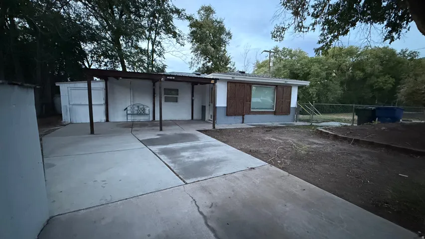 Concrete driveway extending to a covered patio with metal support posts