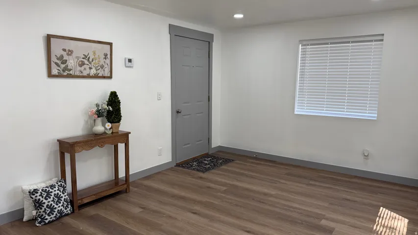 Recessed lighting, wood-finish flooring, and a window with blinds complement the neutral wall finishes