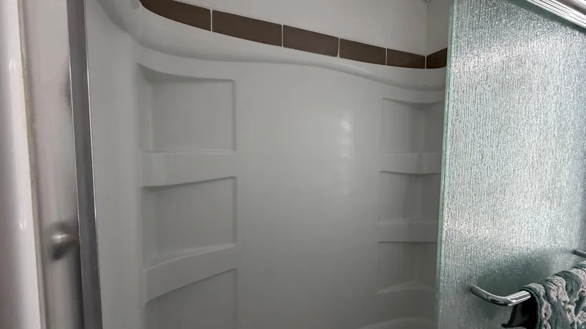 Shower enclosure with integrated shelving and a textured glass sliding door