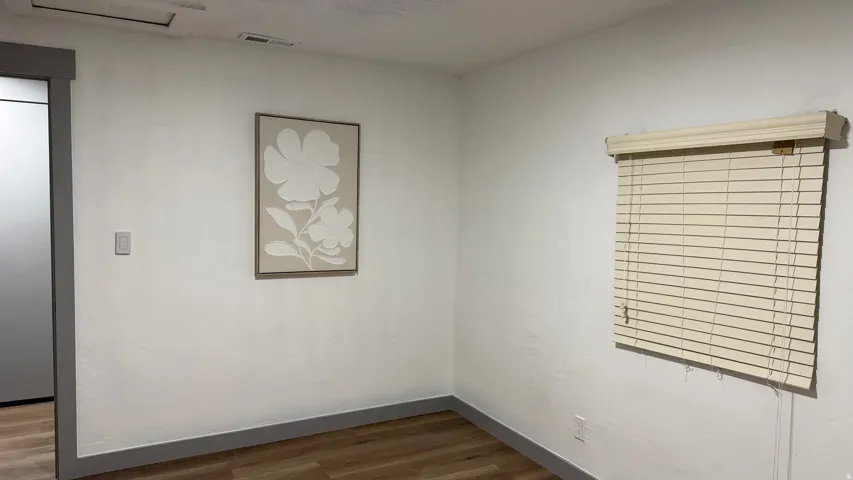 Wood-finish flooring, white walls, and a window with blinds