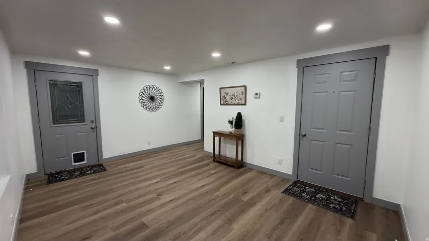Recessed ceiling lighting, wood-finish flooring, white walls, and gray trim around doors