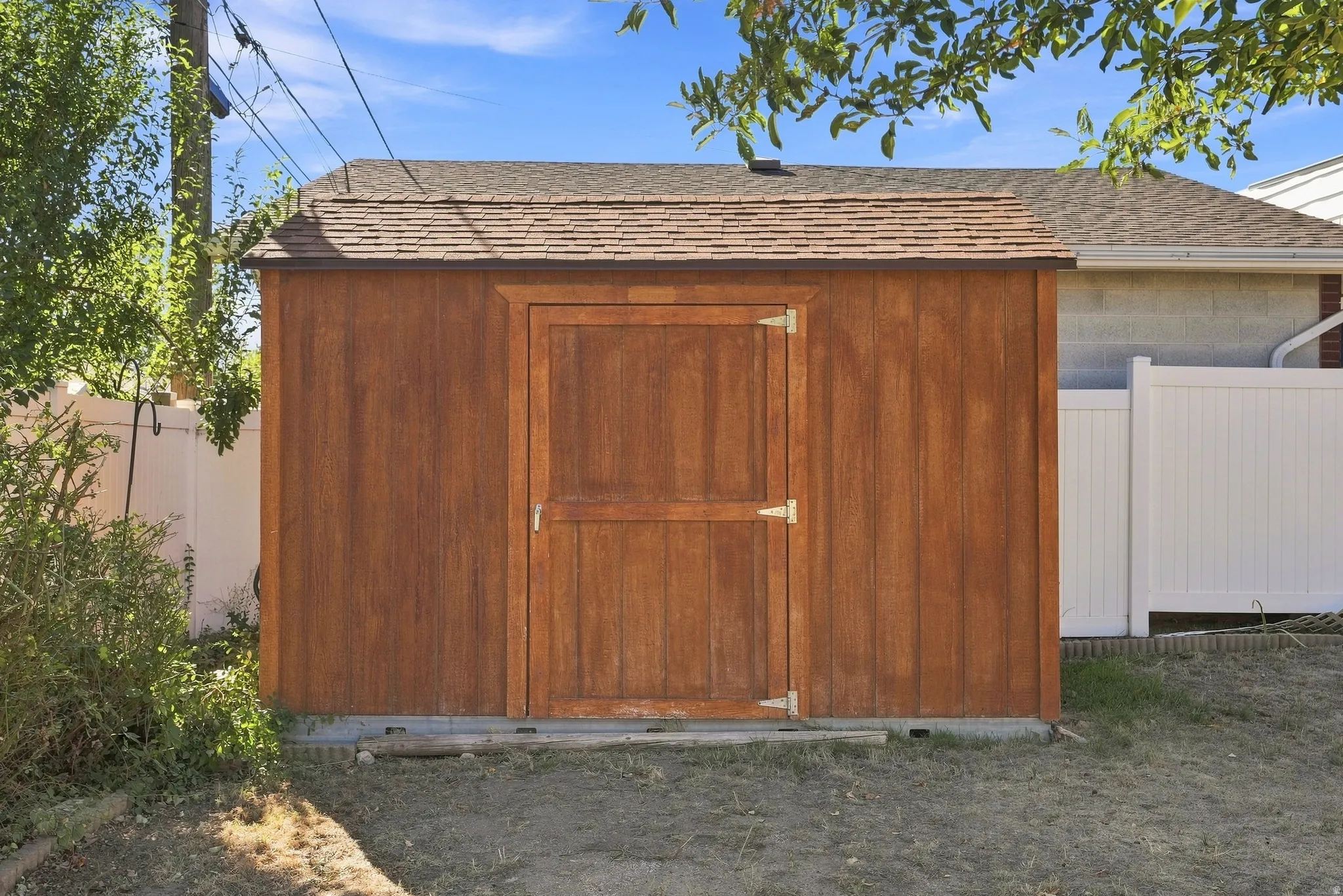 Wooden shed featuring a single door entry, shingle roof, and a gravel perimeter