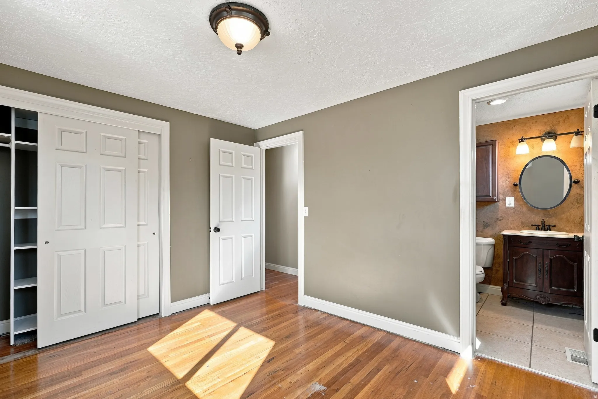 Hardwood flooring, sliding closet doors with built-in shelving, panel interior doors, and a flush mount ceiling light