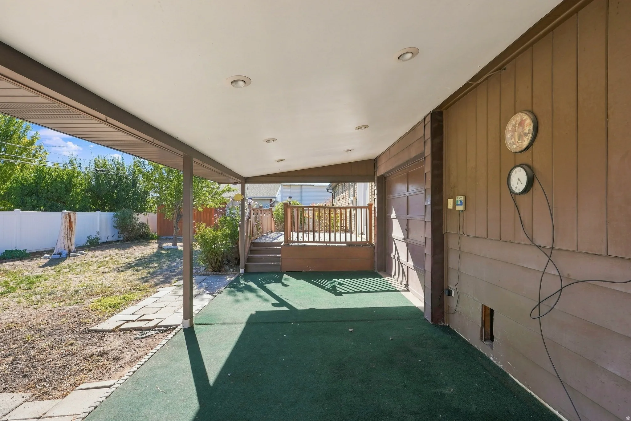 Covered patio with recessed lighting, green outdoor carpeting, and direct access to a raised wooden deck