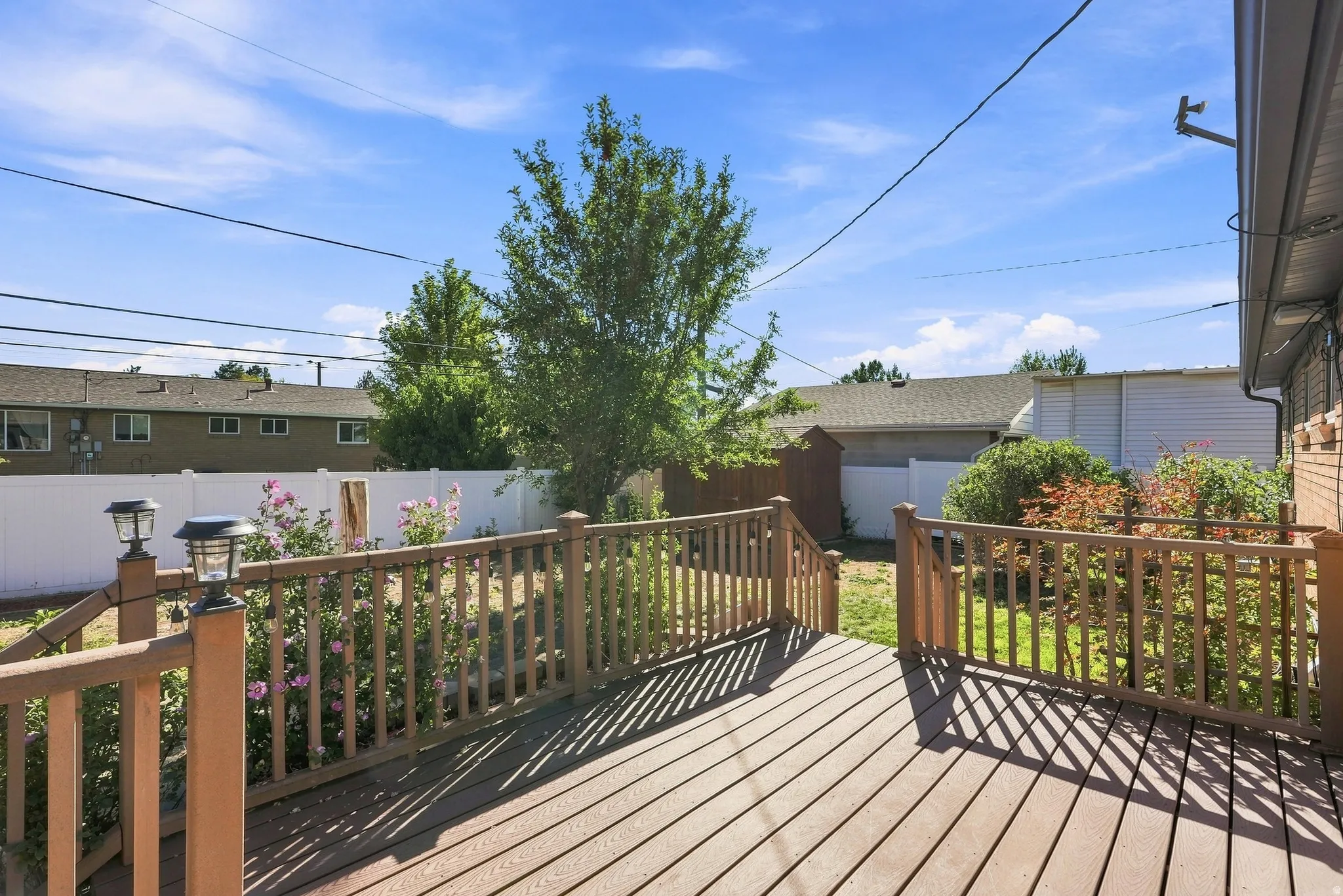Wood-finish deck with railing, featuring built-in solar lights and a partial privacy fence