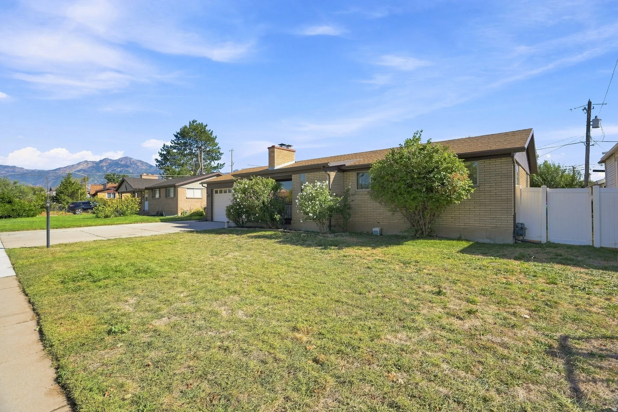 Brick exterior with a brown shingle roof, attached garage, and a concrete driveway