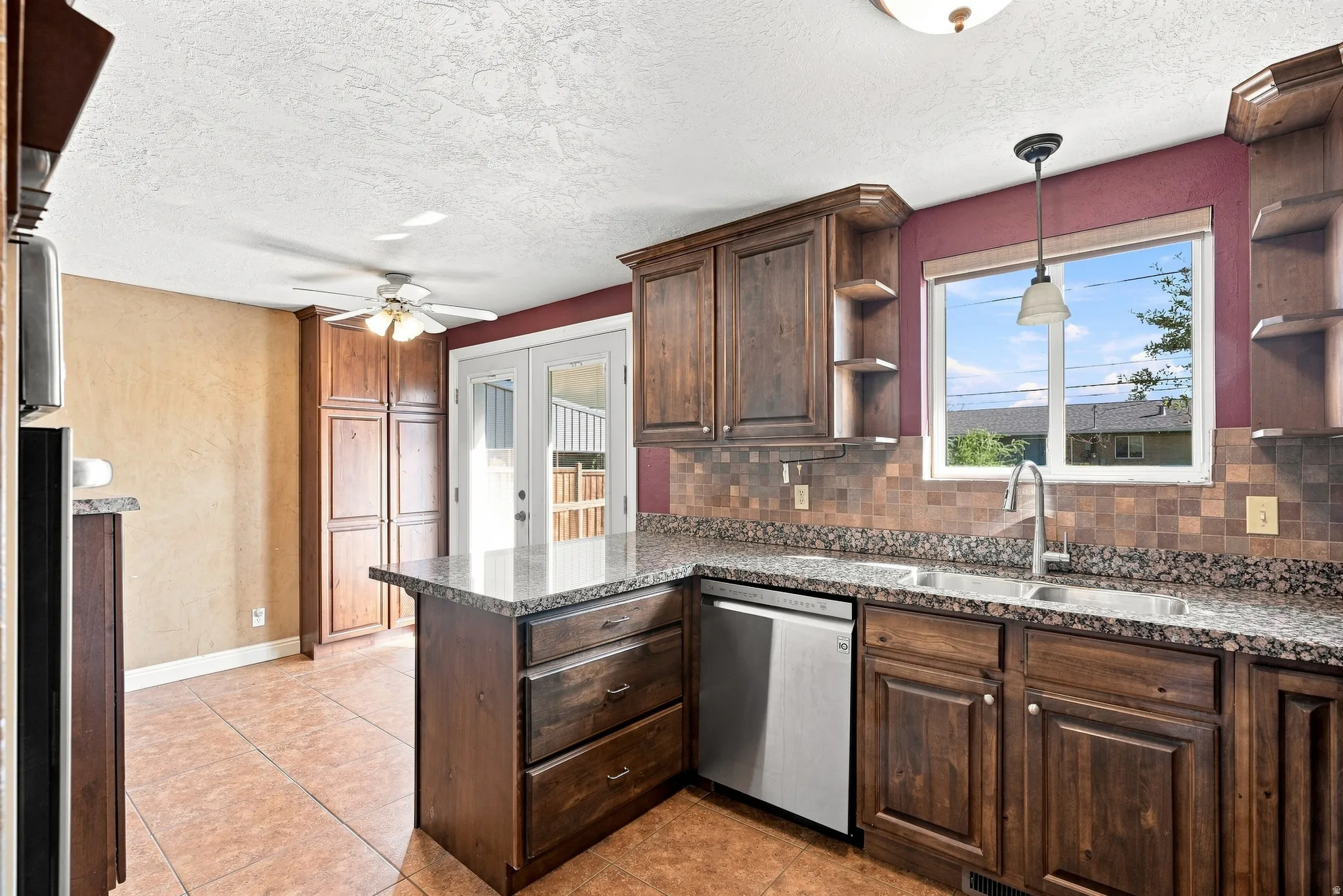 Kitchen featuring wood cabinetry, stone-finish countertops, stainless steel dishwasher, tile flooring, and a tile backsplash