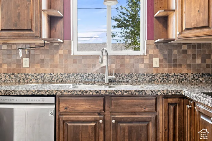Kitchen featuring wood cabinetry, a stainless steel dishwasher, a double basin sink with a gooseneck faucet, a mosaic tile backsplash, and granite countertops