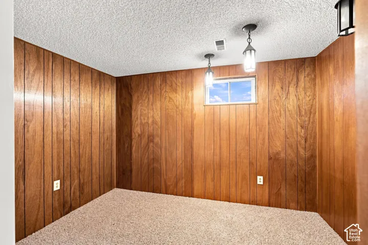 Wood paneling, textured ceiling, carpet flooring, recessed window, and pendant lighting fixtures