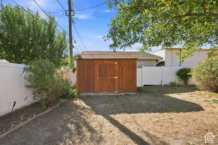 Private backyard featuring a wood storage shed, white privacy fencing, and established trees