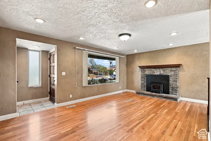 Wood-finish flooring throughout, stone-clad fireplace with wood mantle, recessed lighting, and a front entry with tile flooring and a multi-pane door