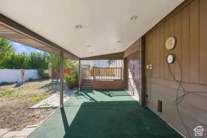 Covered patio with recessed lighting, green outdoor carpeting, and direct access to a raised wooden deck