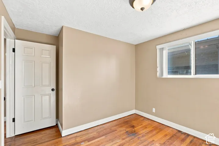 Hardwood flooring, painted walls, white trim, paneled door, and a single window