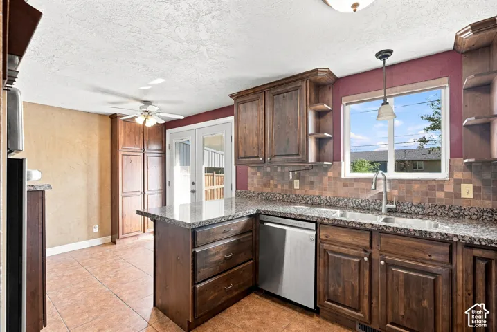 Kitchen featuring wood cabinetry, stone-finish countertops, stainless steel dishwasher, tile flooring, and a tile backsplash