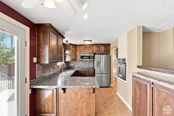 Spacious kitchen featuring dark wood cabinetry, granite-style countertops, stainless steel appliances, and a tile backsplash