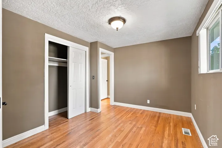 Hardwood flooring, painted walls, white trim, sliding closet doors, and an overhead light fixture